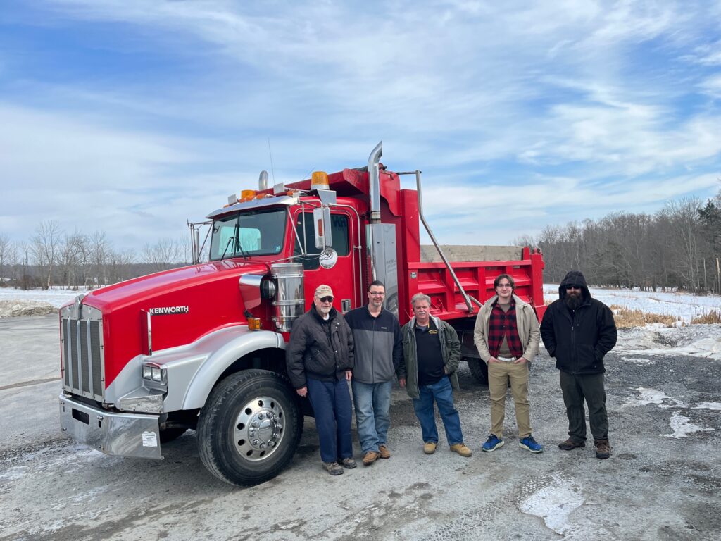 Instructors and students in front of new dump truck